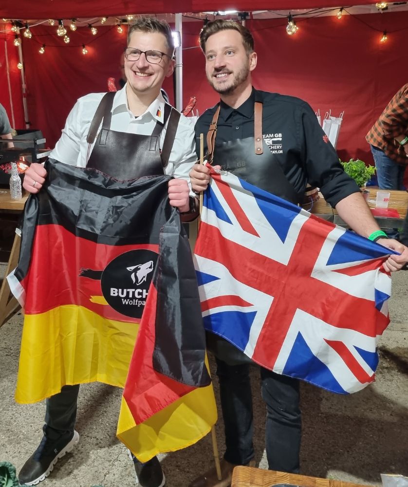 Two male butchers, one holding Union flag and the other holding the German national flag